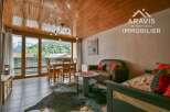 Experience the charm of this stunning property, featuring a cozy living space with a rustic wooden ceiling and large windows that offer breathtaking mountain views.