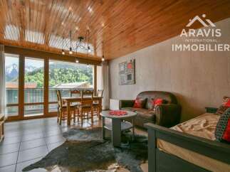 Experience the charm of this stunning property, featuring a cozy living space with a rustic wooden ceiling and large windows that offer breathtaking mountain views.