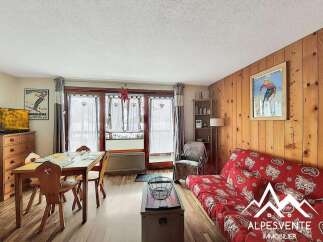Charming alpine living space featuring a cozy dining area with wooden furniture and a vibrant red sofa adorned with heart patterns.