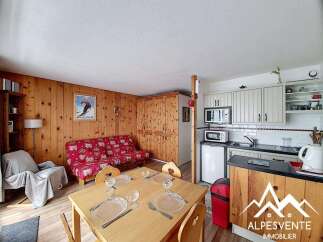 This charming studio apartment features a cozy living area with a vibrant red sofa and a wooden dining table, perfect for intimate meals.