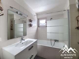 This charming bathroom features a modern vanity with ample storage and a sleek sink, complemented by a large mirror with integrated lighting.