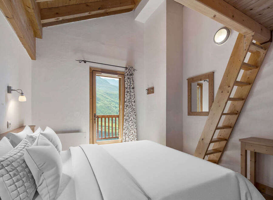 Experience the charm of this cozy bedroom, featuring a unique wooden ladder leading to a loft space.