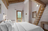 Experience the charm of this cozy bedroom, featuring a unique wooden ladder leading to a loft space.