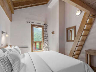Experience the charm of this cozy bedroom, featuring a unique wooden ladder leading to a loft space.