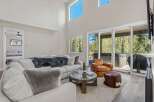 Experience luxury living in this stunning property, featuring a spacious living room with high ceilings and large windows that flood the space with natural light.