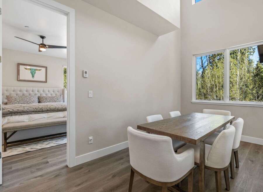 This stunning property features a modern dining area with a beautiful wooden table and comfortable white chairs, perfect for hosting guests.