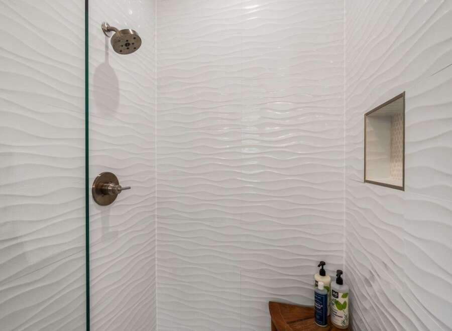 Step into a spa-like oasis with this stunning shower featuring elegant white wave-patterned tiles.