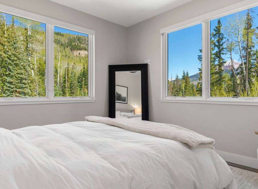 Experience the tranquility of this stunning bedroom, featuring breathtaking mountain views framed by large windows.