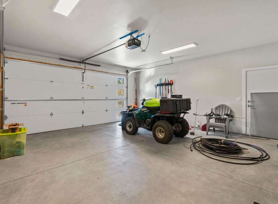 This spacious garage offers ample room for vehicles and storage, featuring a durable concrete floor and bright overhead lighting.