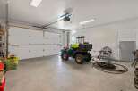This spacious garage offers ample room for vehicles and storage, featuring a durable concrete floor and bright overhead lighting.