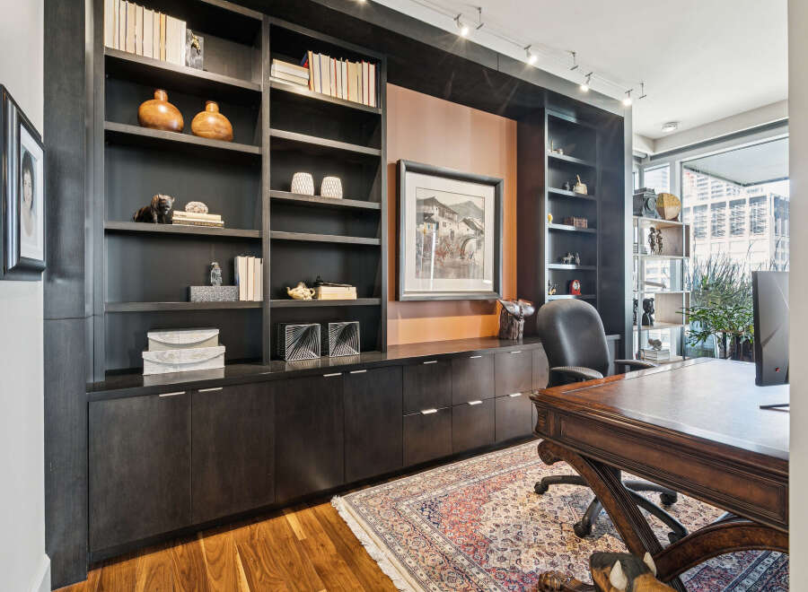 This stunning home office boasts a custom-built dark wood bookcase, providing ample storage and a sophisticated aesthetic.