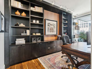 This stunning home office boasts a custom-built dark wood bookcase, providing ample storage and a sophisticated aesthetic.