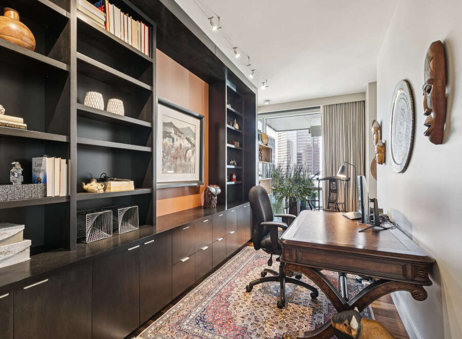 This stunning home office boasts a sophisticated design with custom built-in shelving and a rich, dark wood desk.