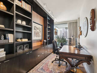 This stunning home office boasts a sophisticated design with custom built-in shelving and a rich, dark wood desk.