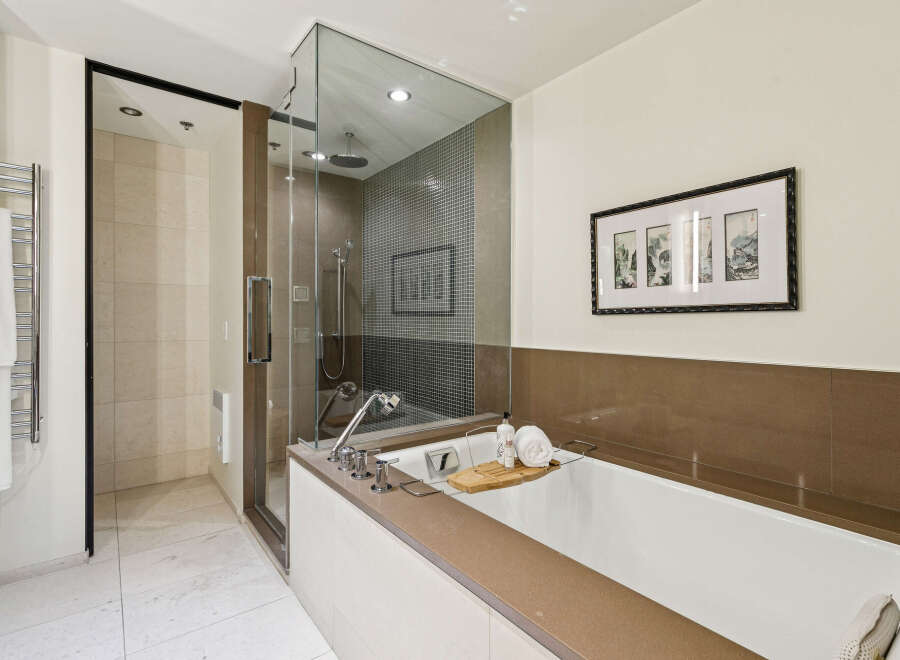 Indulge in luxury within this stunning bathroom, featuring a sleek glass-enclosed shower and a deep soaking tub.