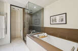 Indulge in luxury within this stunning bathroom, featuring a sleek glass-enclosed shower and a deep soaking tub.
