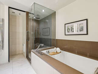 Indulge in luxury within this stunning bathroom, featuring a sleek glass-enclosed shower and a deep soaking tub.