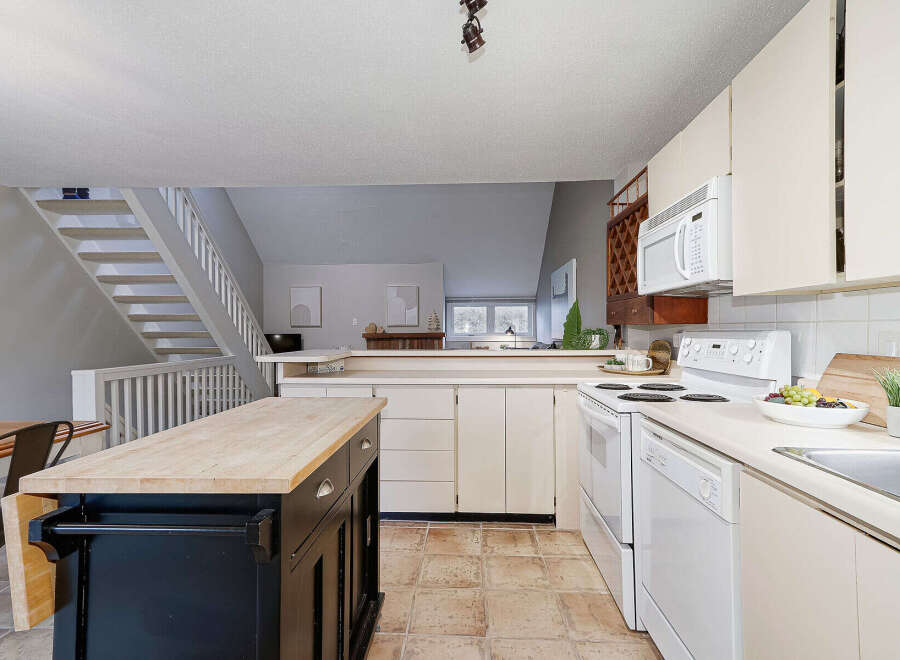 Step into this inviting kitchen, boasting a stylish island with a butcher block countertop, perfect for meal prep and casual dining.