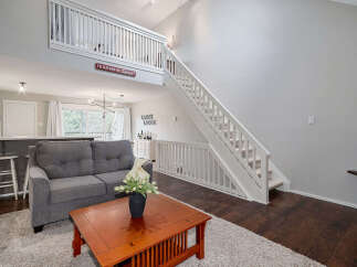 This stunning property boasts a spacious living area with a cozy gray sofa and a charming wooden coffee table, perfect for relaxing.