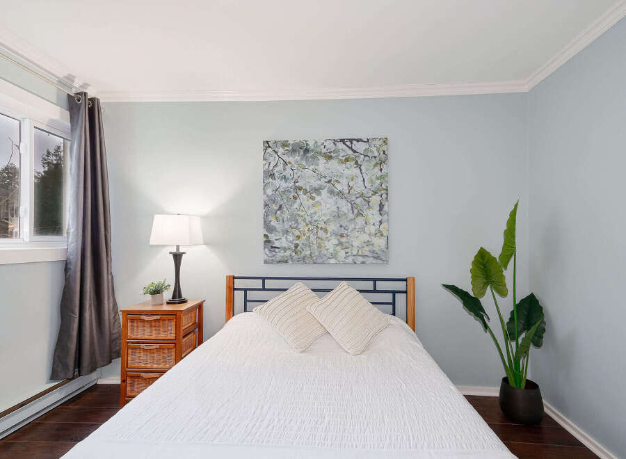 This inviting bedroom showcases a serene ambiance with its soft blue walls and natural light.