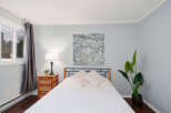 This inviting bedroom showcases a serene ambiance with its soft blue walls and natural light.