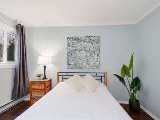 This inviting bedroom showcases a serene ambiance with its soft blue walls and natural light.