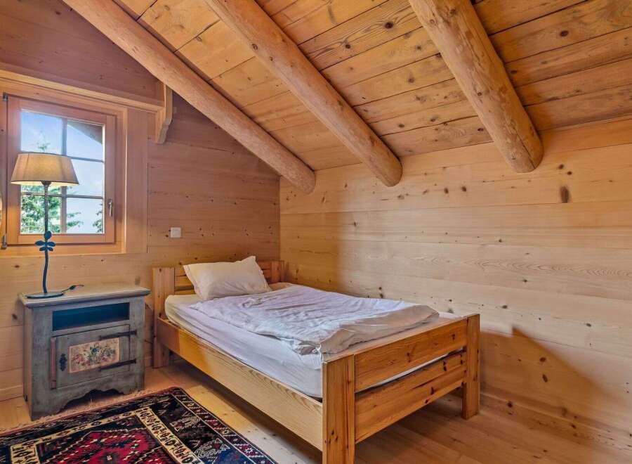 Discover the charm of this cozy bedroom, featuring a rustic wooden bed and a warm, inviting atmosphere.