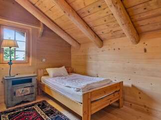Discover the charm of this cozy bedroom, featuring a rustic wooden bed and a warm, inviting atmosphere.