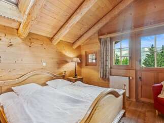 Experience the charm of this cozy bedroom, featuring a warm wooden interior and a comfortable bed.