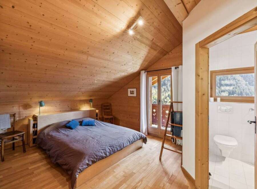 Discover the charm of this cozy bedroom, featuring a warm wooden interior and a comfortable bed.
