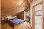 Discover the charm of this cozy bedroom, featuring a warm wooden interior and a comfortable bed.