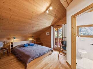 Discover the charm of this cozy bedroom, featuring a warm wooden interior and a comfortable bed.