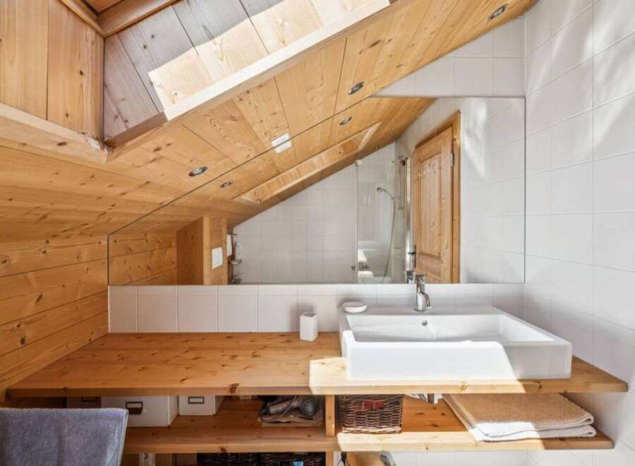 This stunning bathroom boasts a unique design with a sloped wooden ceiling, creating a cozy and inviting atmosphere.