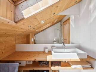 This stunning bathroom boasts a unique design with a sloped wooden ceiling, creating a cozy and inviting atmosphere.