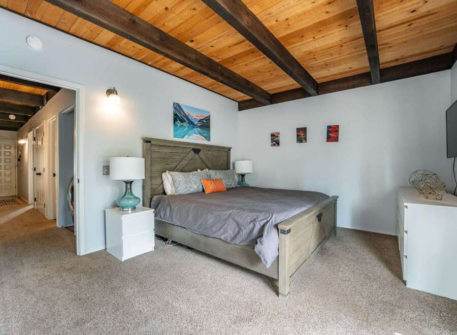Step into this inviting bedroom featuring a stunning wooden ceiling and a cozy ambiance.