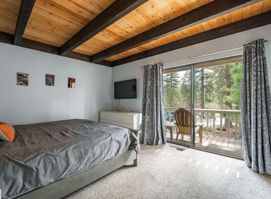This stunning bedroom boasts a rustic charm with its wooden ceiling beams and a serene view of the surrounding nature.