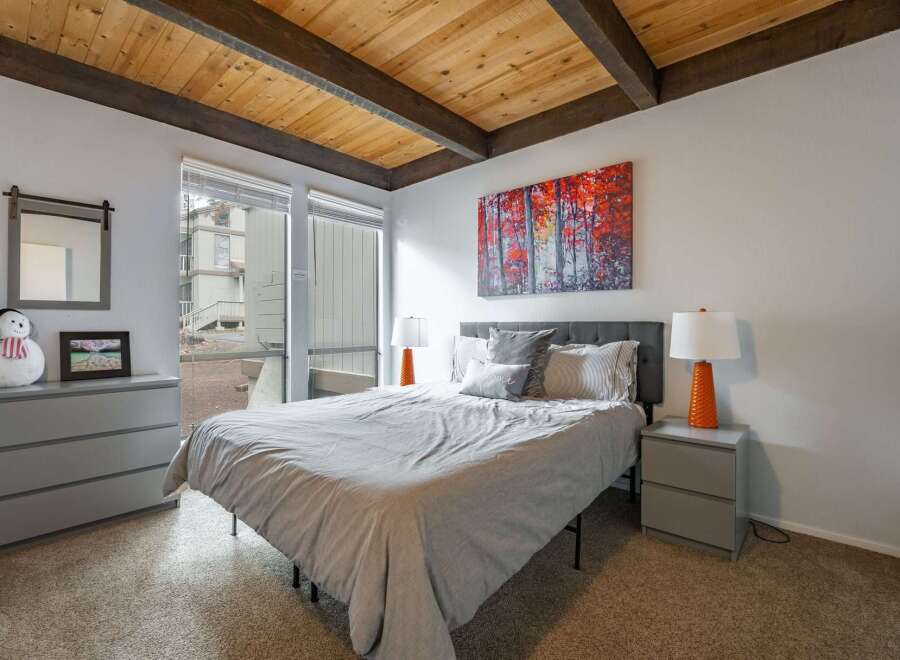 This cozy bedroom features a stylish design with a wooden ceiling and a comfortable bed.