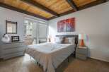 This cozy bedroom features a stylish design with a wooden ceiling and a comfortable bed.