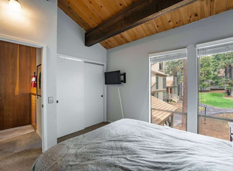 Discover the charm of this inviting bedroom, featuring a cozy bed and a mounted TV for entertainment.