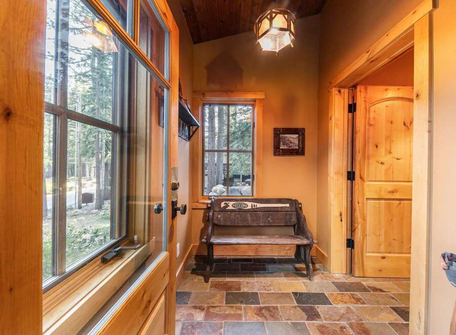 Step into this inviting entryway, showcasing a rustic bench and a welcoming 'Welcome' sign.