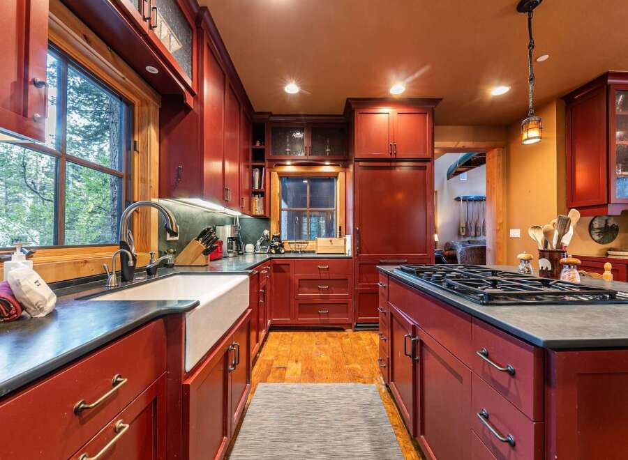 This stunning kitchen boasts rich, red cabinetry and a spacious layout, perfect for culinary enthusiasts.