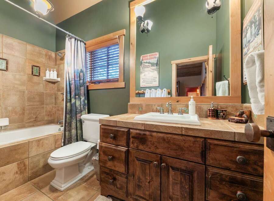 Step into this charming bathroom, featuring a rustic wooden vanity and a cozy ambiance.
