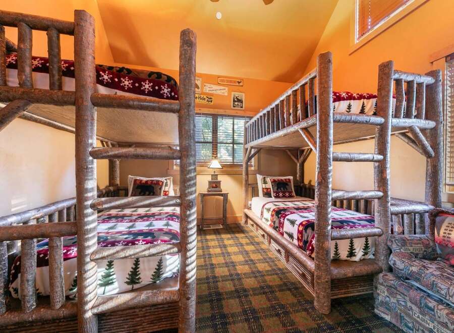 This charming cabin-style bedroom features two sets of rustic bunk beds, perfect for accommodating multiple guests or family members.