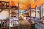 This charming cabin-style bedroom features two sets of rustic bunk beds, perfect for accommodating multiple guests or family members.