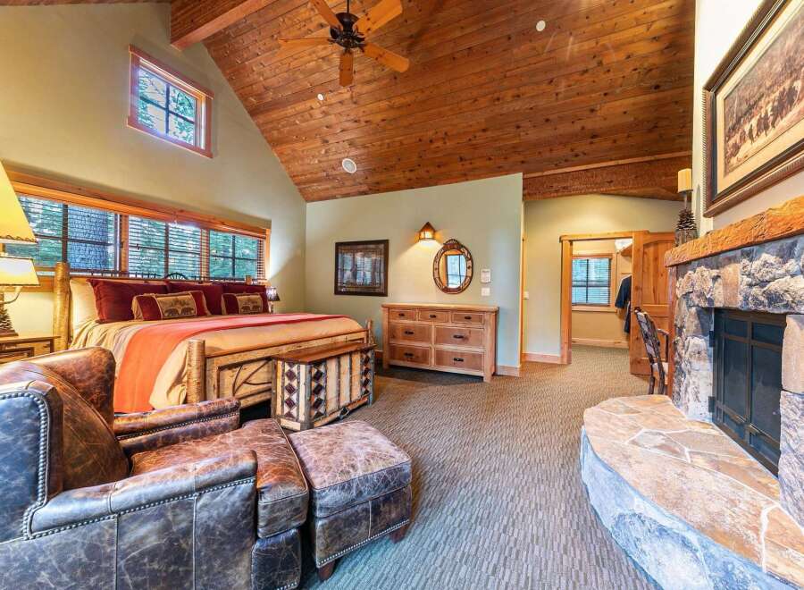 Experience rustic luxury in this stunning bedroom featuring a cozy fireplace and a king-sized bed.
