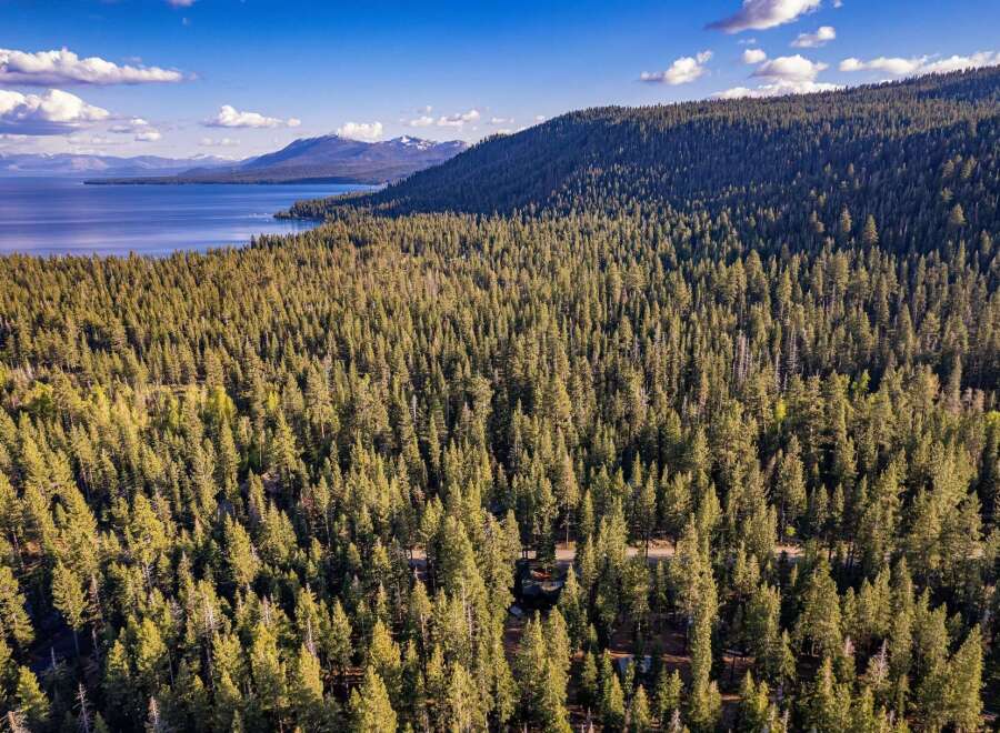 Discover the tranquility of this stunning property, nestled amidst a lush forest and offering breathtaking views of a serene lake and majestic mountains.