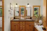 This stunning bathroom boasts a double vanity with a beautiful wood cabinet, offering ample storage and a touch of rustic elegance.