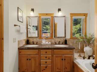 This stunning bathroom boasts a double vanity with a beautiful wood cabinet, offering ample storage and a touch of rustic elegance.