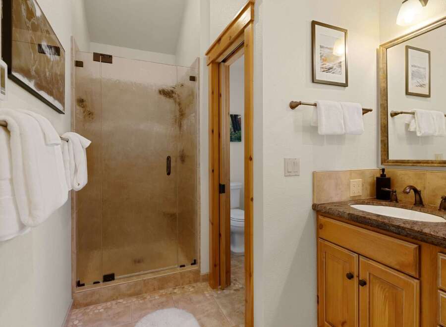 Step into a beautifully designed bathroom featuring a spacious glass shower and elegant wooden accents.