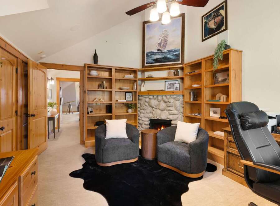 Step into luxury with this stunning property, featuring a cozy living room with a fireplace and built-in bookshelves.
